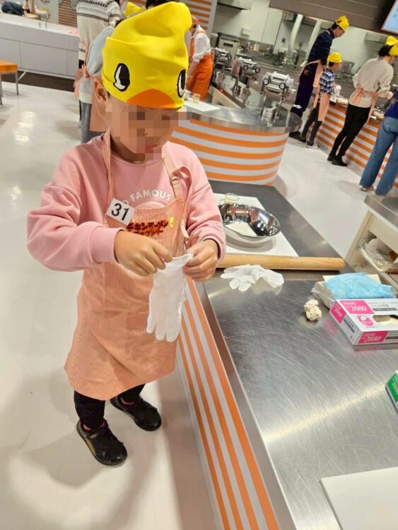 チキンラーメンファクトリー体験で、子どもが手袋をつけて作業前の準備をしている様子