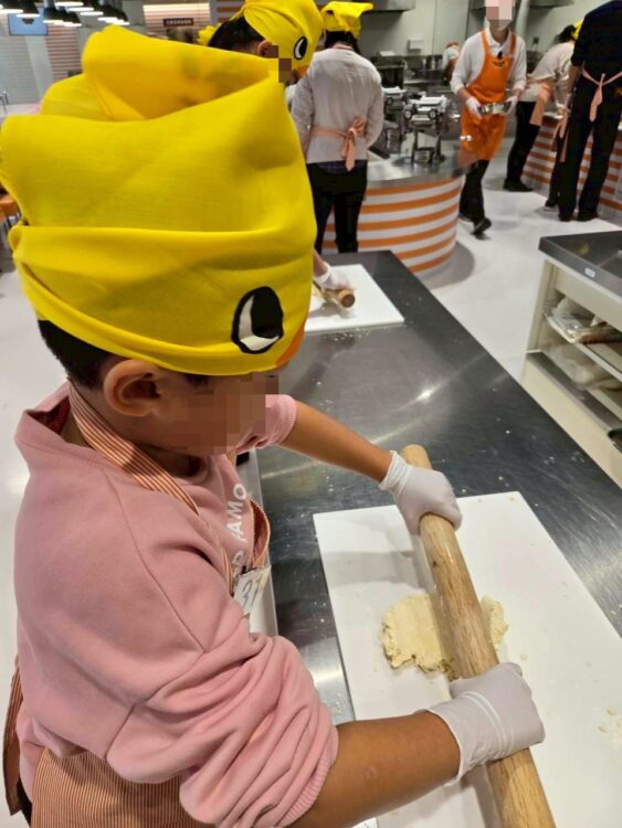 チキンラーメンファクトリー体験で、子どもがめん棒を使って麺の生地をのばしている様子