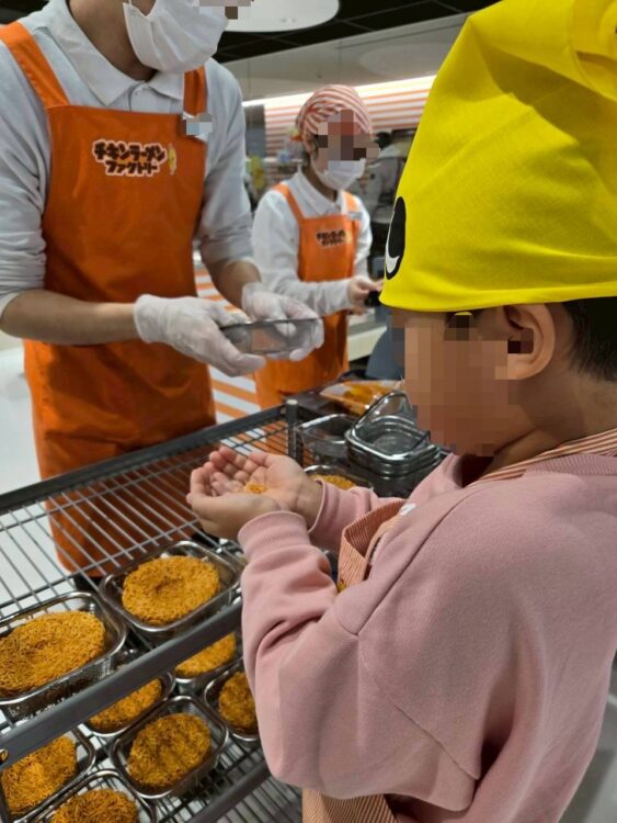 チキンラーメンファクトリーで、パッケージに入れた後に入り切らなかった麺を試食している様子