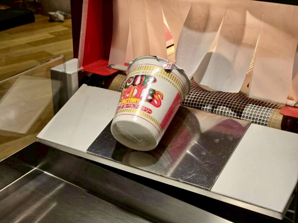 フィルム包装されたマイカップヌードルが機械から出てくる様子