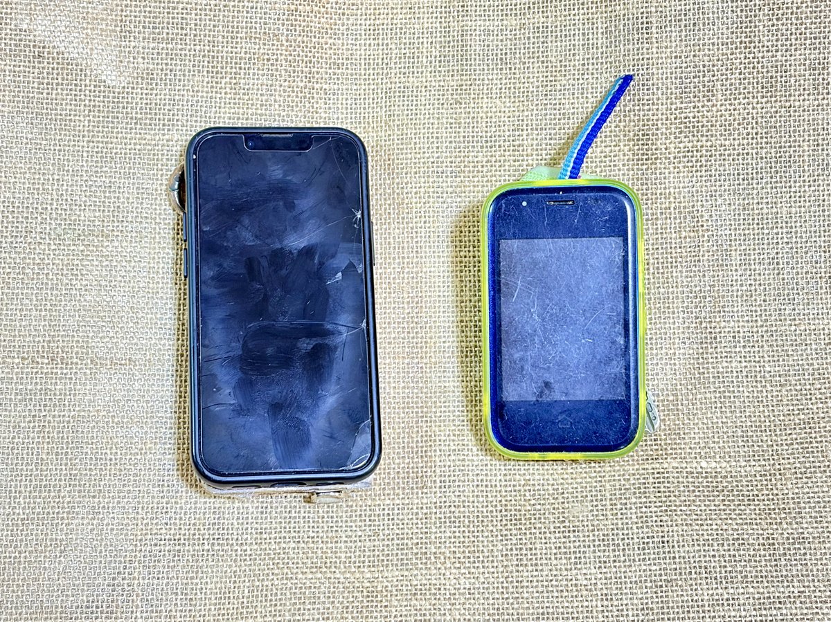 兄のiPhoneと弟のキッズ携帯を並べたところ。大きさのちがいがよく分かる