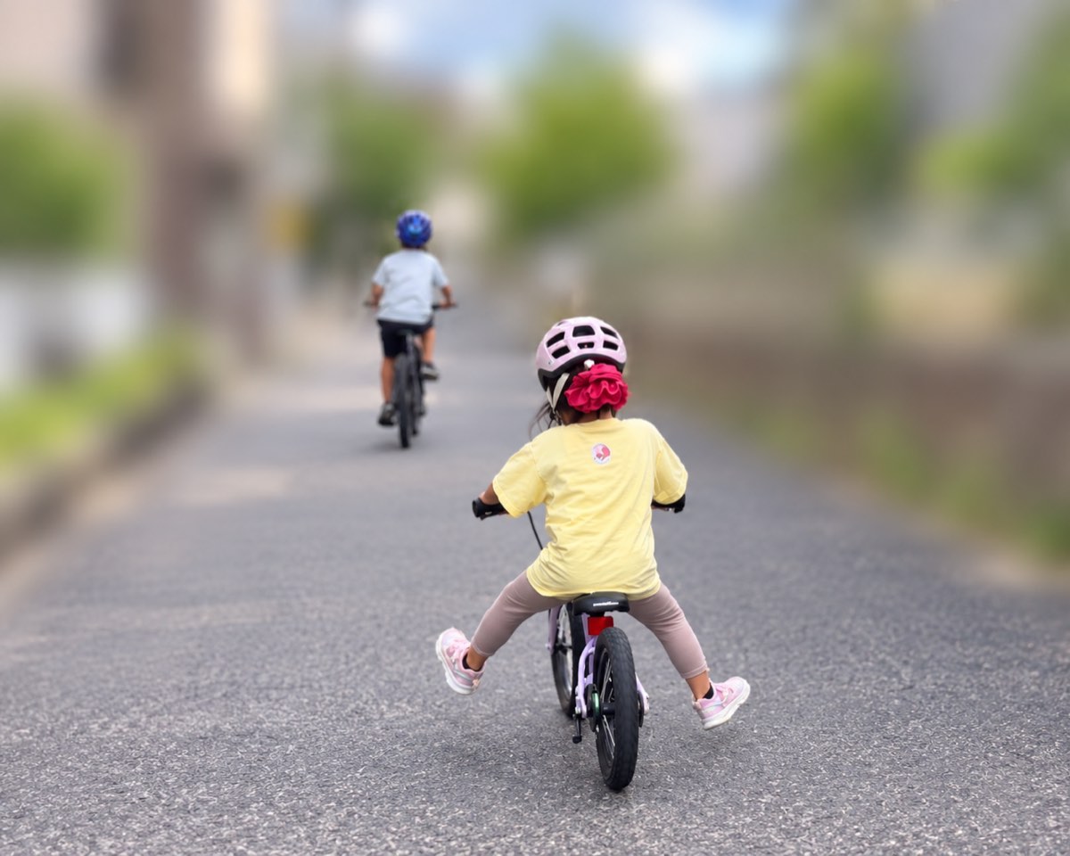 へんしんバイクC14で両足を浮かせて走る4歳児。前を兄が自転車で走っている