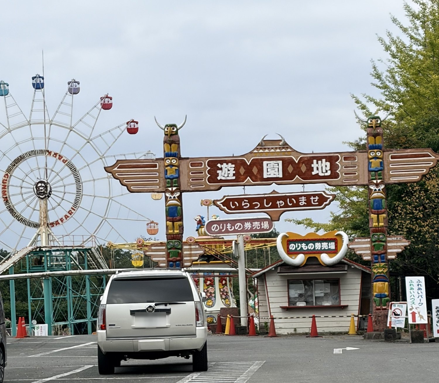 園内の遊園地の門と観覧車。のりもの券売場の前に、コーンとロープが置かれている
